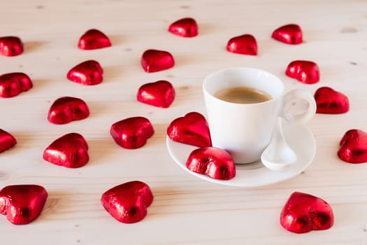 Red chocolate hearts and a cup of italian coffee on a table