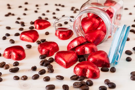 Red hearts in a glass jar and coffee beans on a table