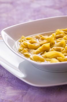 Tortellini in broth in a white square plate