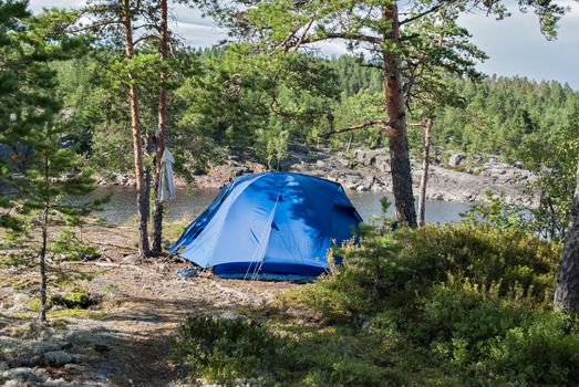 Blue tourist tent on the rocky shore of Lake Ladoga in Karelia.