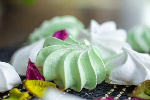 White and green marshmallow dessert composition on black background