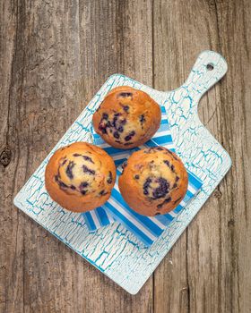 Fresh blueberry muffins photographed against a vintage background.