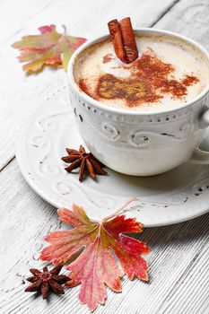 Coffee cup with cinnamon and star anise on autumn background