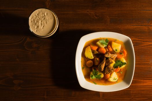 Traditional Irish Stew with a pint of beer on a table seen from above.