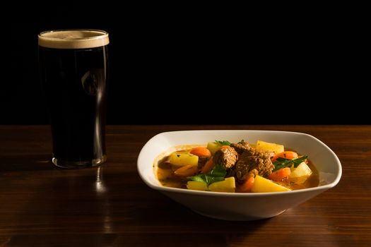 Traditional Irish Stew with a pint of beer on a table.