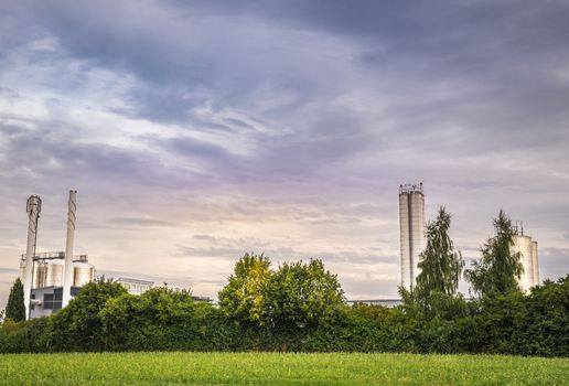 Image with a heat and electricity factory, based on an environmentally safe technology, surrounded by green nature.