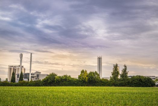 Image with an electric power plant with all its units, in the middle of green vegetation, under a dramatic sky.