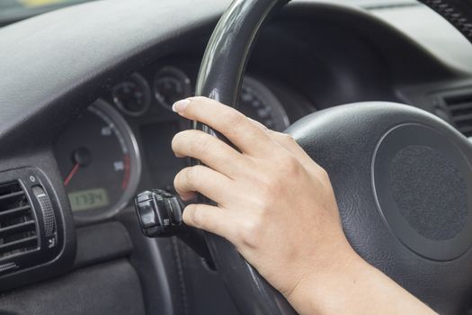 Arm girls with trendy manicure holds the steering wheel in the car