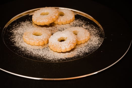 Five biscuits canestrelli on a plate of steel and icing sugar above