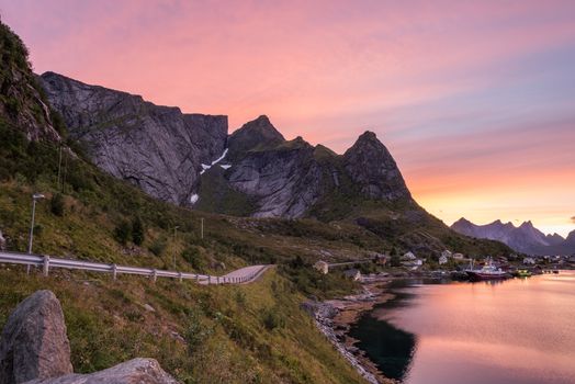 Reine, Lofoten, Norway. Fishing village with sharp mountain peaks at sunset. Showing the road leading into the village.