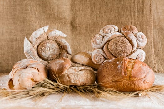 Several kind of bread with sheaves of wheat and jute background