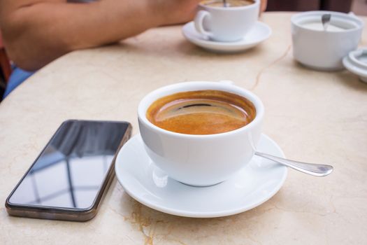 Coffee break in cafe, cup of coffee and smartphone on marble table top