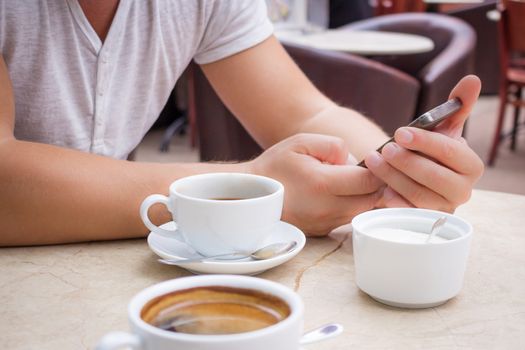 Man sits with smartphone at marble table with cup of coffee