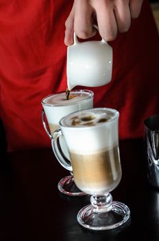 the bartender Barista behind the counter making coffee latte, pouring and prevents