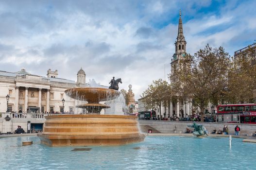 London, United Kingdom - November 8, 2014: Fountain at crowded Trafalgar Square. It is one of the most popular tourist attraction in London, often considered the heart of London.