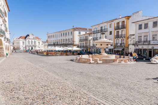 EVORA, PORTUGAL - AUGUST 25, 2014: Giraldo Square in the center of Evora with renaissance fountain and bars where people having a drink.