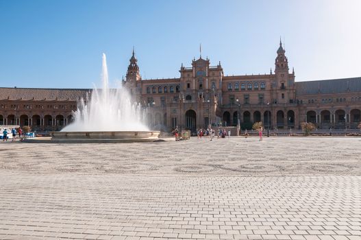 Seville, Spain - August 28, 2015: Tourists visit Plaza de Espana in Seville. It is a landmark example of the Renaissance Revival style in Spanish architecture.