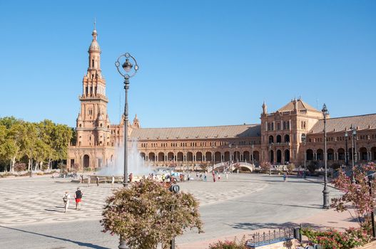 Seville, Spain - August 28, 2015: Tourists visit Plaza de Espana in Seville. It is a landmark example of the Renaissance Revival style in Spanish architecture.