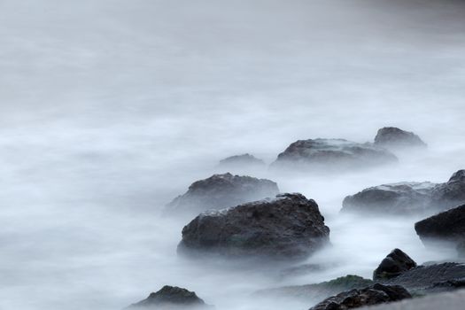 Morning fog over the rocky shore of the sea