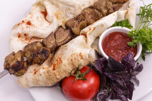 shashlik on a plate with sauce, onions and pita