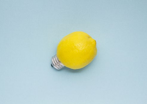 Creative concept photo of a lemon with a bulb on blue background.