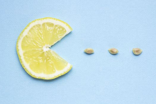 Creative concept photo of a lemon slice eating seeds on blue background.