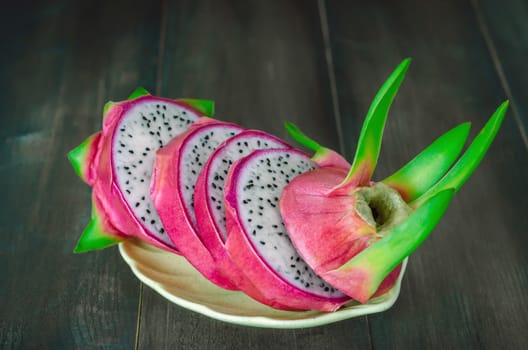 Ripe Dragon fruit  with slice on dish over wooden background , still life