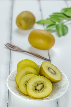 golden kiwi fruit and sliced on dish over white wooden background
