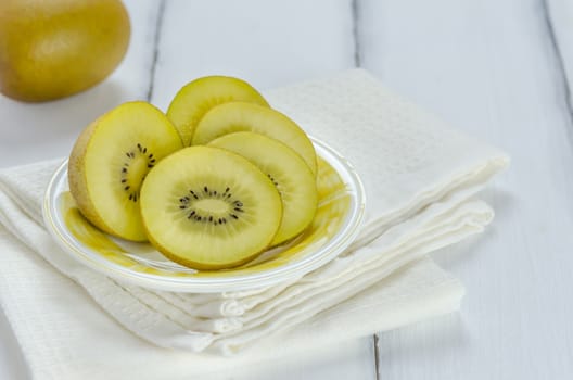 golden kiwi fruit and sliced on dish over white wooden background