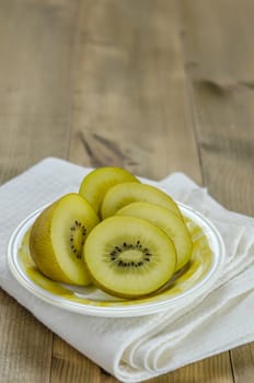 golden kiwi fruit and sliced on dish over wooden background