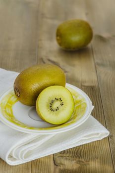 golden kiwi fruit and sliced on dish over wooden background