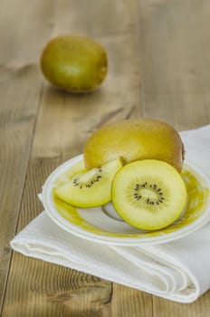 golden kiwi fruit and sliced on dish over wooden background
