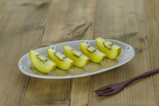 sliced of golden kiwi fruit  on dish over wooden background