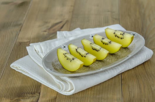 sliced of golden kiwi fruit  on dish over wooden background