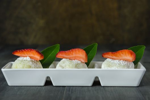 Strawberry Daifuku Mochi Japanese dessert on white plate over wooden background, still life