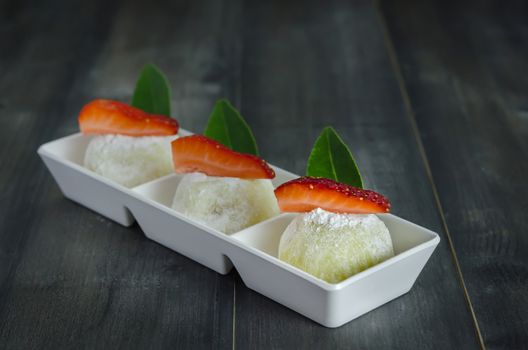 Strawberry Daifuku Mochi Japanese dessert on white plate over wooden background, still life