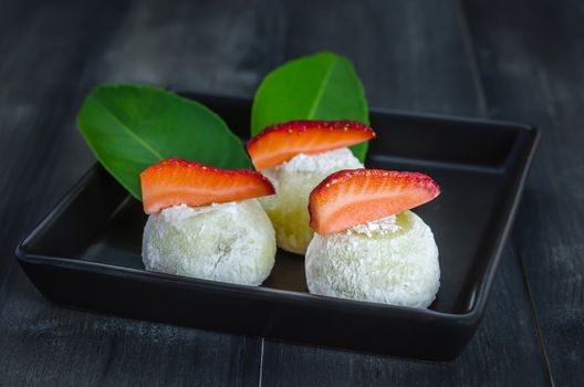 Strawberry Daifuku Mochi Japanese dessert on black dish over wooden background