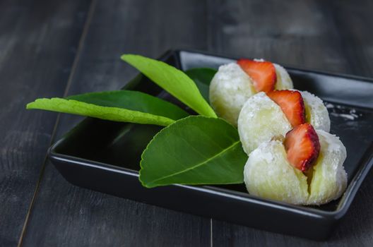 Strawberry Daifuku Mochi Japanese dessert on black dish over wooden background