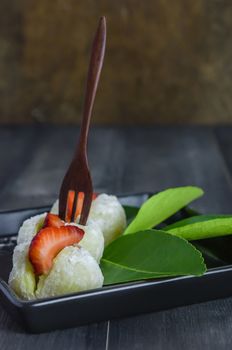 Strawberry Daifuku Mochi Japanese dessert on black dish over wooden background