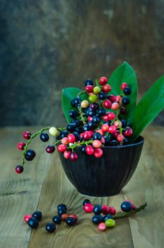 Thai Blueberry in black bowl over wooden background , still life