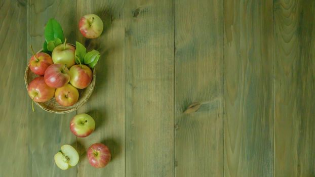 Top view red and yellow apple with leaves and  bamboo basket on wooden background with free space for text