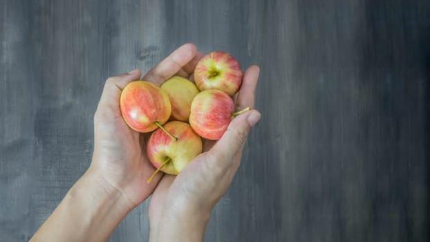 human hand holding red and yellow apple  on wooden background , Top view