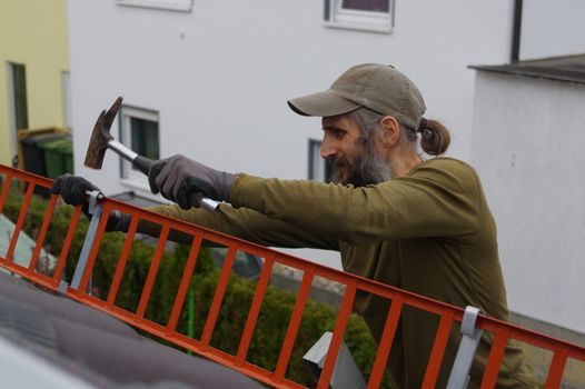 roofer or worker with a hammer on the roof