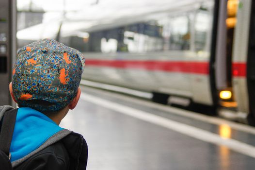 DRESDEN - 17. July: a boy with a cap waits for train on railway platform on Dresden Central Railway Station. An ICE express train drives past the platform. 17. July 2015 - Dresden, Germany.