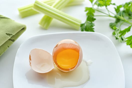 Raw broken egg rests on a plate, and Greens