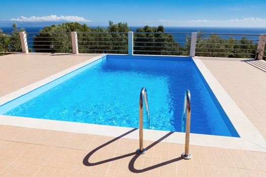 Water in blue swimming pool near sea in greece during summer season