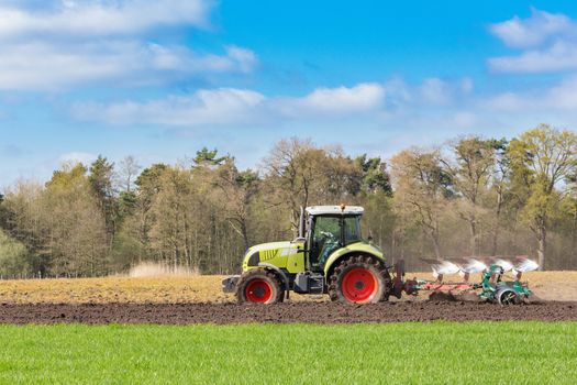 Peasant on tractor plowing sandy soil in spring season