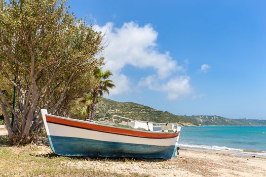 Colorful boat lying on greek beach with blue sea and sky
