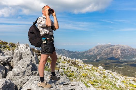 Dutch man on rocky mountain looking through binoculars