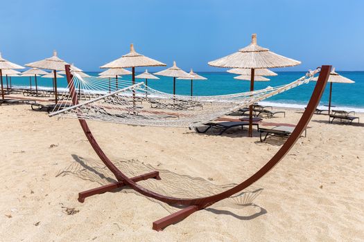 Hammock with beach umbrellas and loungers at greek coast with sea